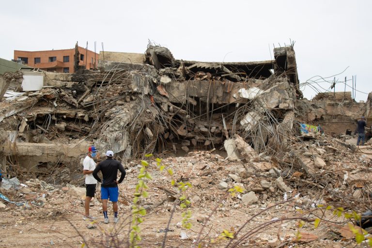 Two people looking at a damaged building