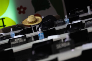 A straw hat balanced on a suitcase, surrounded by tables and chairs and country signs